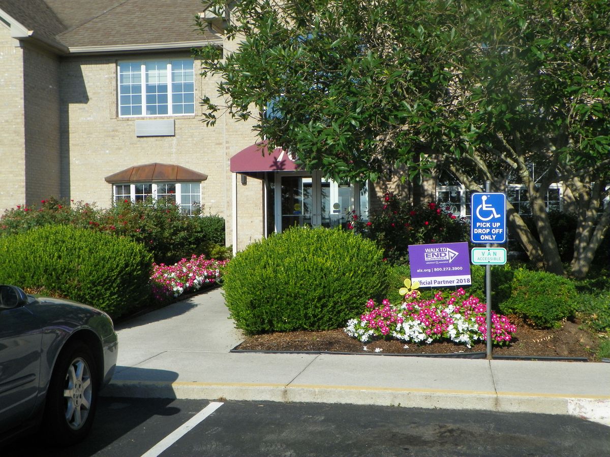 Entrance to a building with landscaped flowers and a designated parking space.