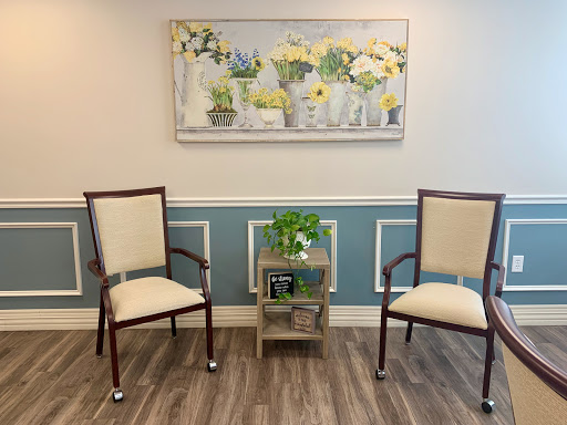 A serene waiting area featuring two elegant chairs and a decorative floral painting.