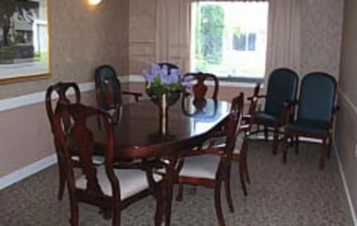 A cozy dining room with a polished wooden table and chairs, complemented by a window view.