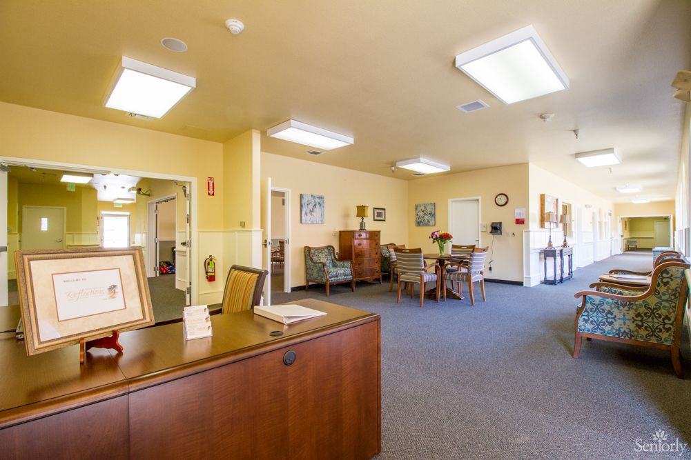 A view of a spacious office reception area with desks, chairs, and decor under bright indoor lighting.