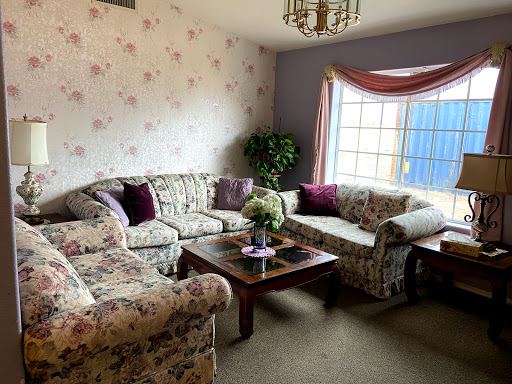 A cozy living room featuring floral patterned sofas and a bright window.