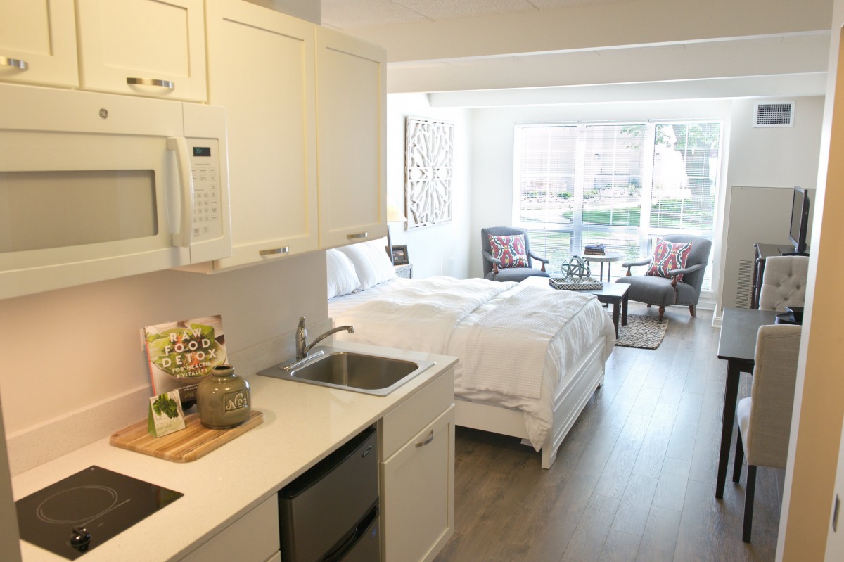 A modern studio apartment with an integrated kitchen and bedroom area, featuring bright decor and cozy furnishings.