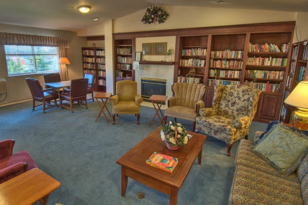 A cozy library with comfortable seating and a fireplace surrounded by bookshelves.