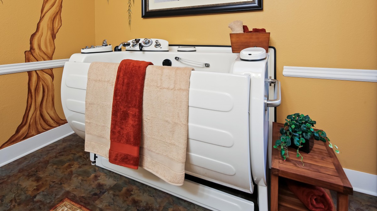 An accessible bathtub with towels hanging over the side in a warmly decorated bathroom.