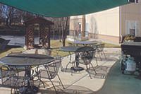 An outdoor patio area with tables and chairs under shade.