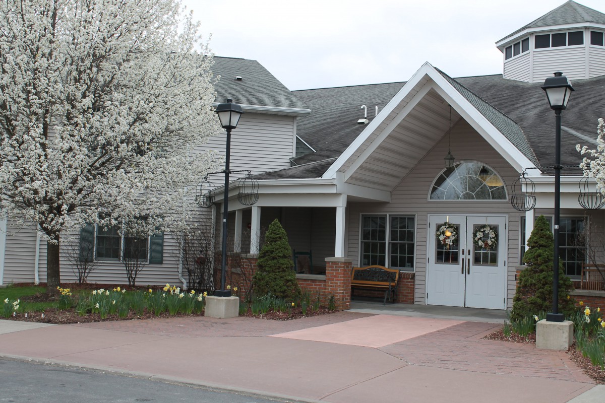 A residential building with a peaked entrance and blooming trees.