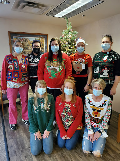 A joyful team celebrating the holiday season in their festive ugly sweaters and masks.