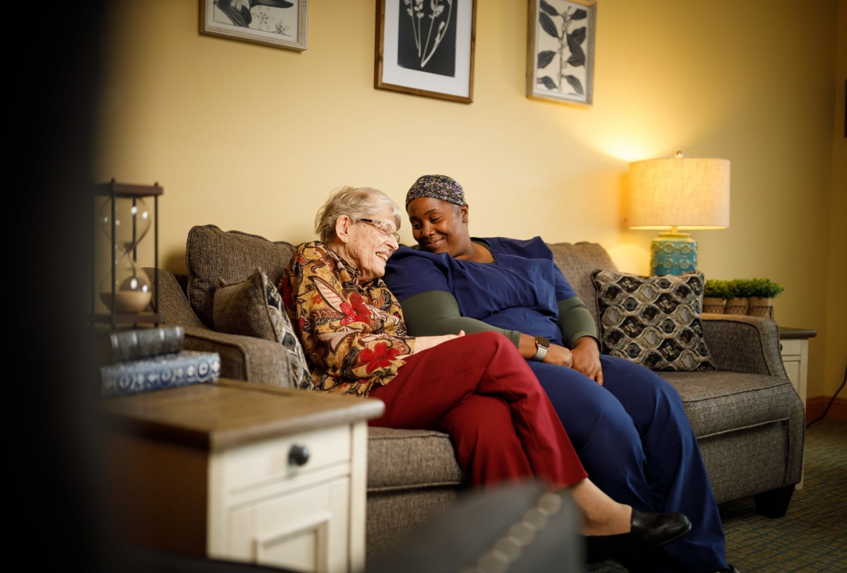 Two people share a warm conversation on the couch in a cozy living room setting.