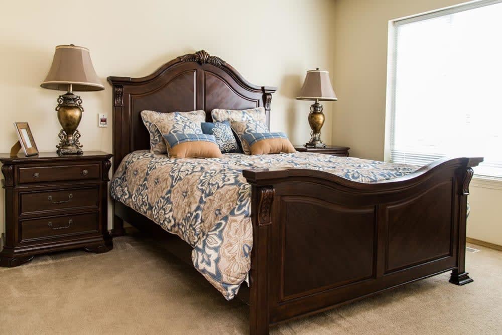 A cozy bedroom with a wooden bed frame and matching nightstands, adorned with elegant bedding and decorative pillows.