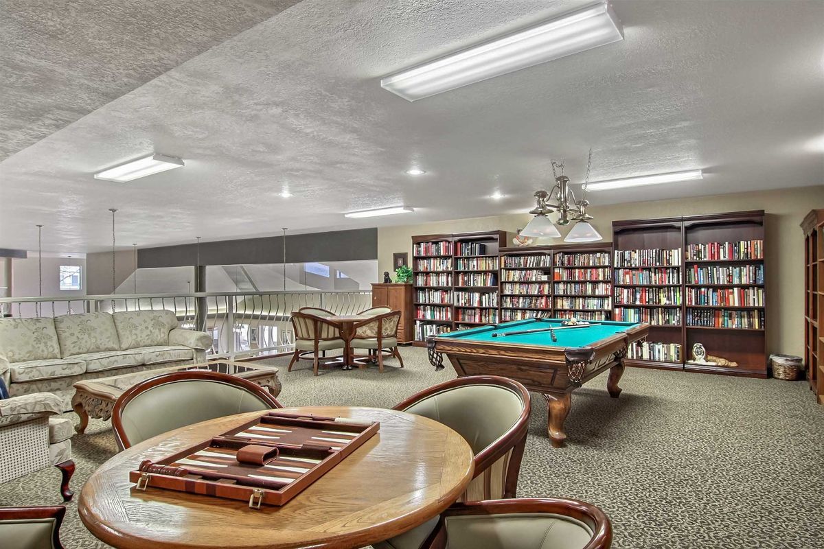 A cozy recreational space featuring bookshelves, a pool table, and a seating area for games or reading.