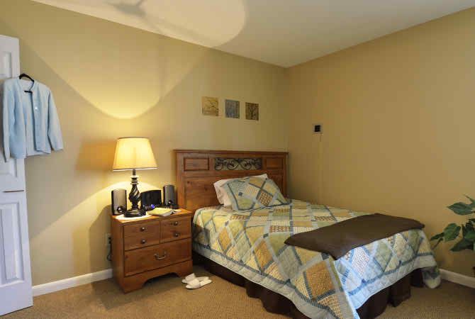 A cozy bedroom with a single bed, nightstand, and lamp.