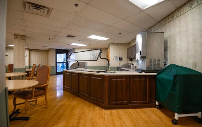 An empty cafeteria kitchen with a wooden counter and chairs.