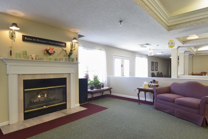 A cozy living room with a fireplace, couch, and large windows letting in natural light.