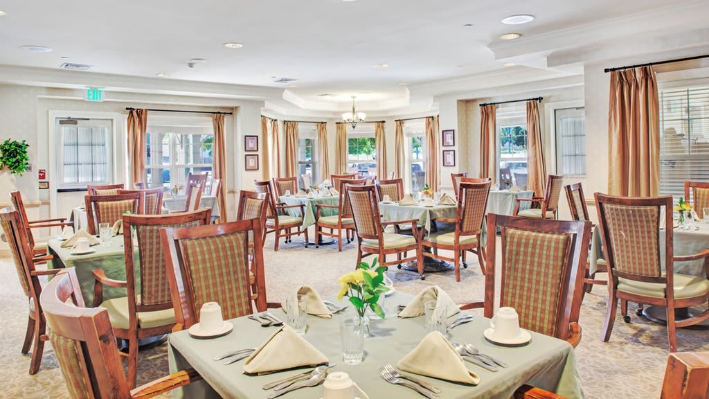 A well-lit dining room with elegantly set tables and comfortable chairs.