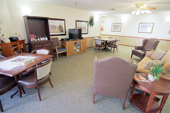 A cozy room with several tables, chairs, a television, and wall decorations.