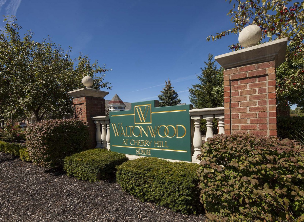 Entrance sign to Ravenwood Club Estates surrounded by landscaping and brick pillars.