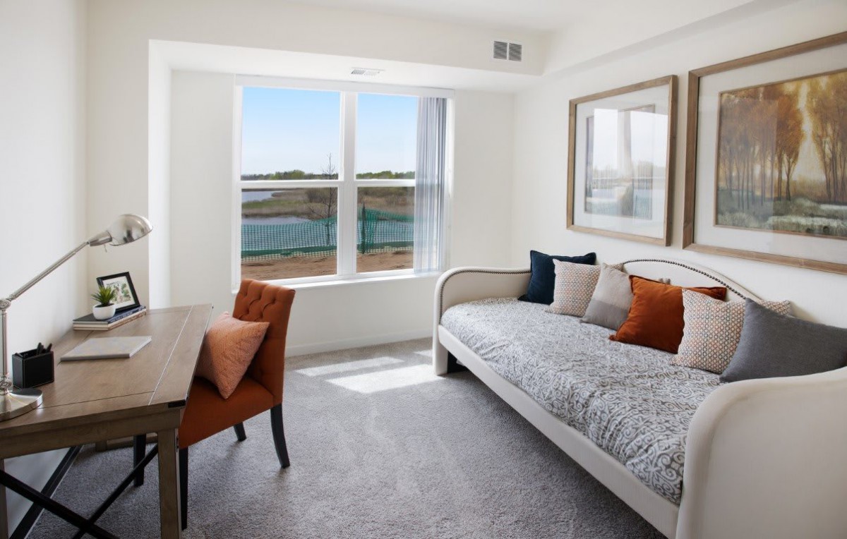 A bright and modern room featuring a daybed, a chair by the window, and tasteful decor with ample natural light.