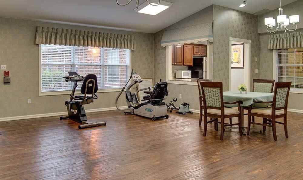 A small indoor gym area with exercise equipment and a table with chairs.
