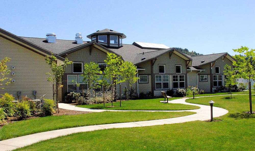 A well-maintained residential building surrounded by lush greenery and a winding pathway.