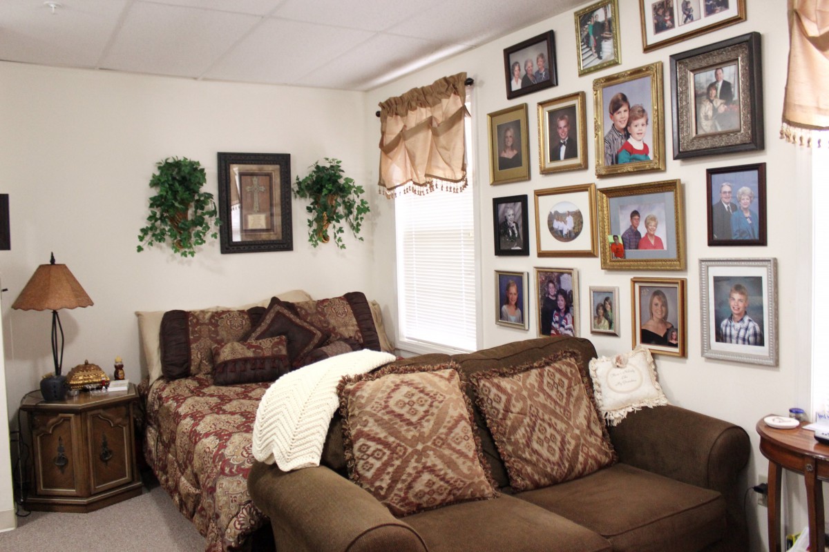 A cozy living room with a sofa and a wall adorned with family photos and decorative frames.