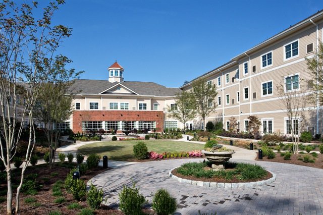 A well-maintained residential building with a landscaped courtyard under a clear blue sky.