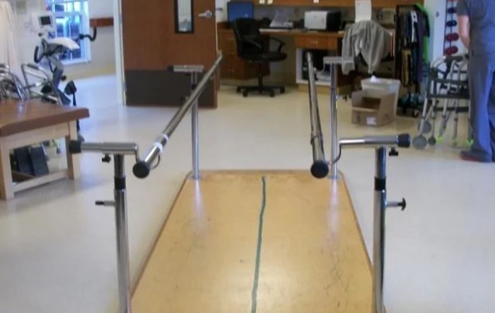 A set of parallel bars used for physical rehabilitation exercises in a facility.