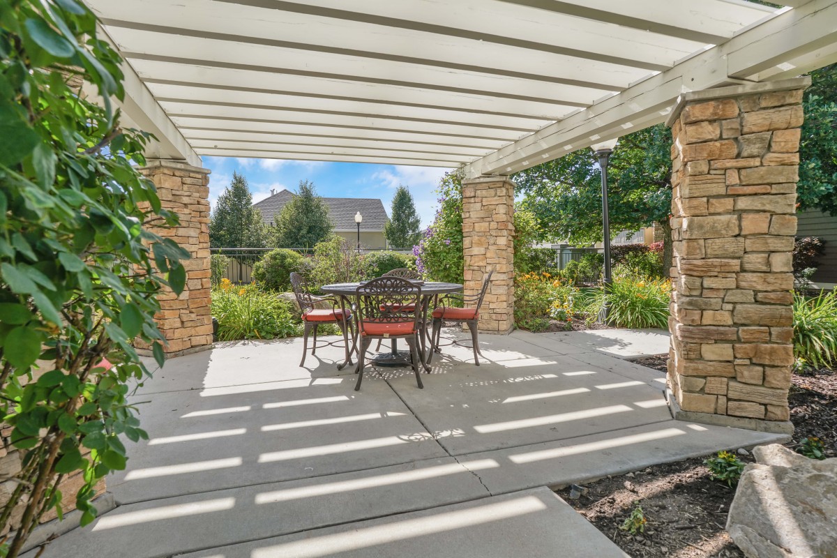 A beautiful garden patio with a pergola providing shade over an outdoor dining set.