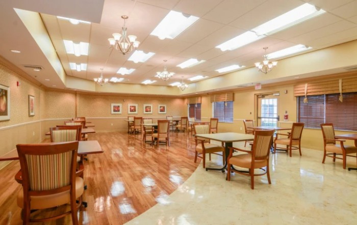 A spacious and well-lit dining area with wooden floors, neatly arranged tables and chairs.