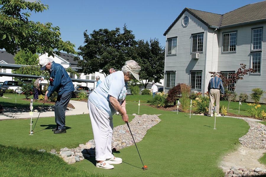 Seniors enjoying a game of mini golf on a sunny day.