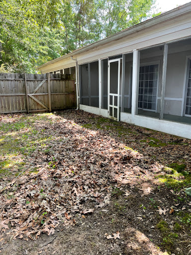 A serene backyard area with fallen leaves and a fenced-off screened porch.