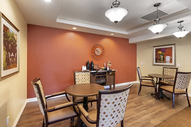 A cozy dining area with wooden tables and chairs, warm lighting, and decorative elements.