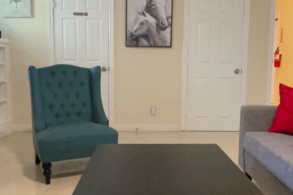 A cozy living room with a teal armchair, a coffee table, and horse-themed artwork on the wall.