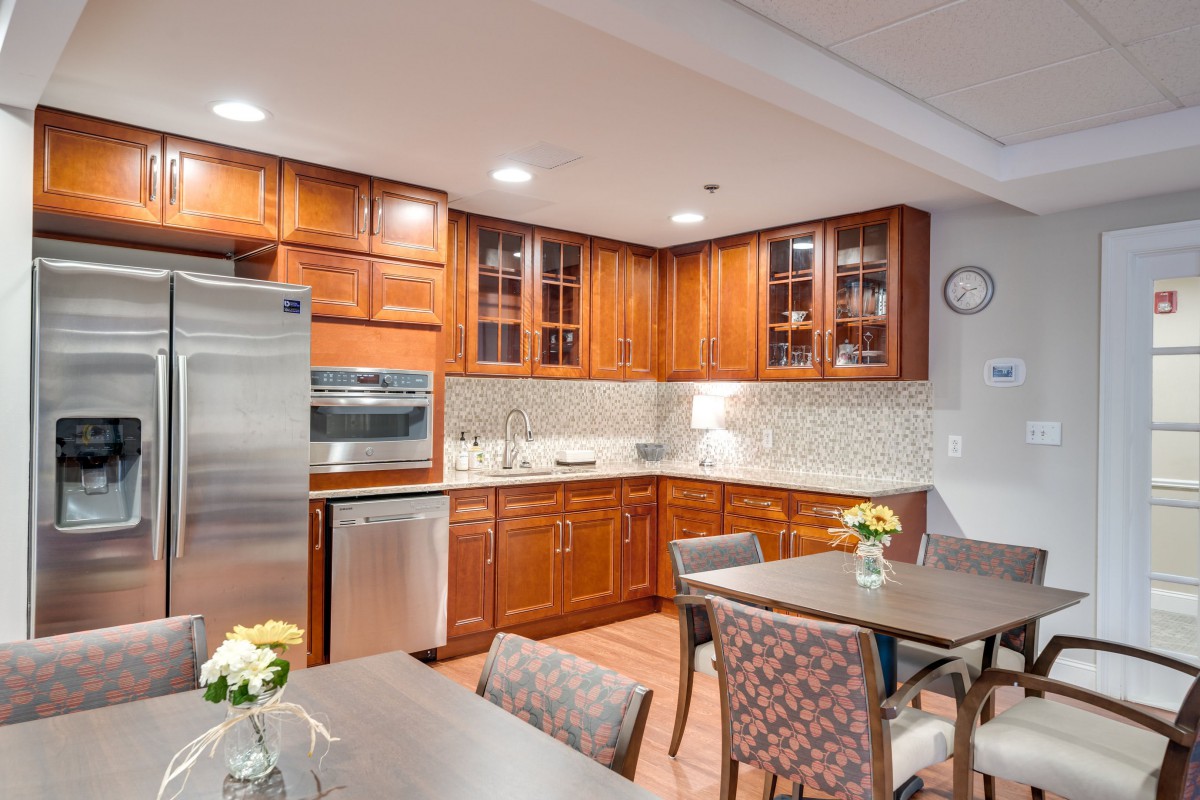 A modern kitchen with wooden cabinets, stainless steel appliances, and a dining area decorated with flowers.