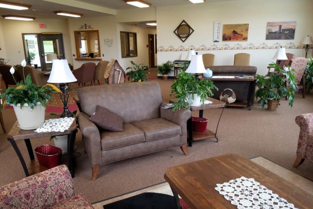 A cozy living room with comfortable seating, plants, and a piano in the corner.