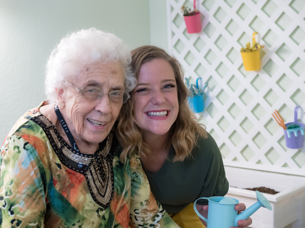 A joyful moment shared between an elderly woman and a young woman, smiling together indoors.