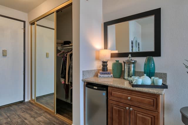 A cozy room corner featuring a mini fridge, elegant decor, and a closet with sliding doors.