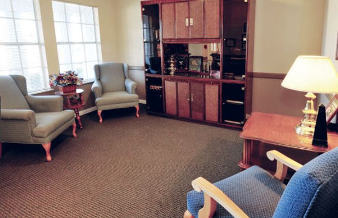 A cozy living room with armchairs and a wooden cabinet.