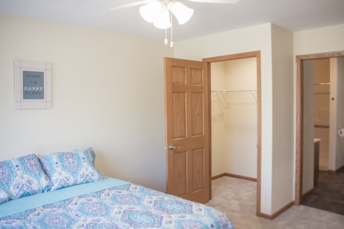 A simple bedroom with a bed, closet, and ceiling fan.