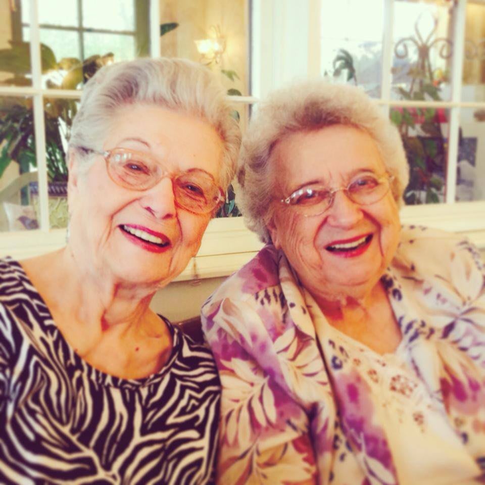 Two elderly women smiling together indoors.