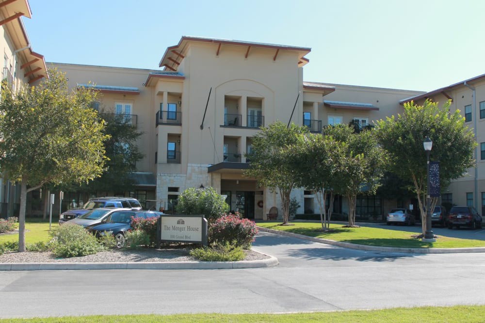 A residential building with surrounding trees and parked cars.