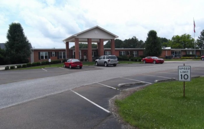 A brick building with a parking lot and several cars in front.