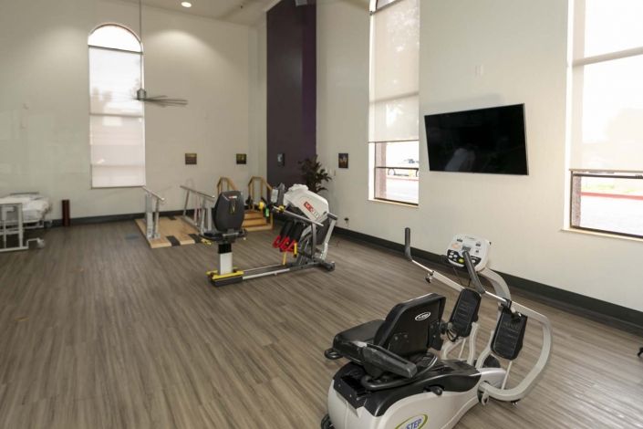 A well-equipped fitness center with exercise machines and a TV.