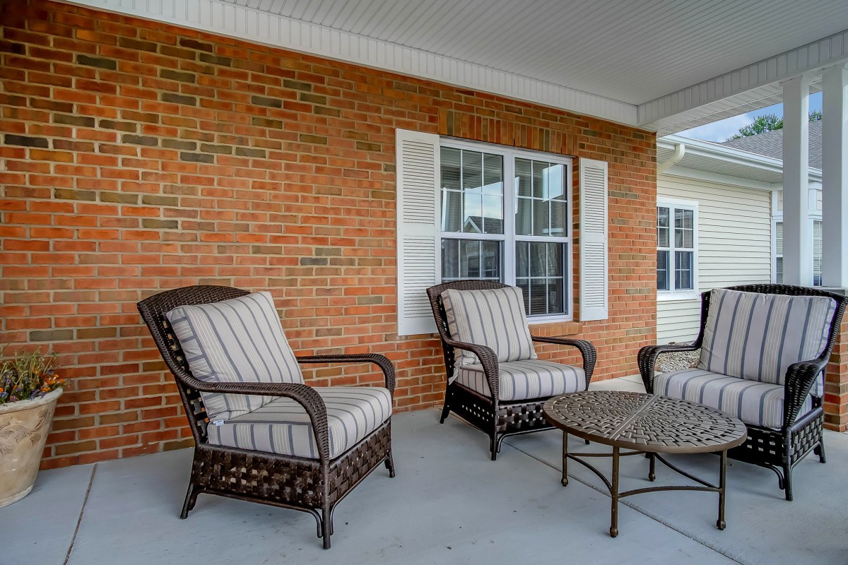 A cozy outdoor patio area with wicker chairs and a table set against a brick wall.
