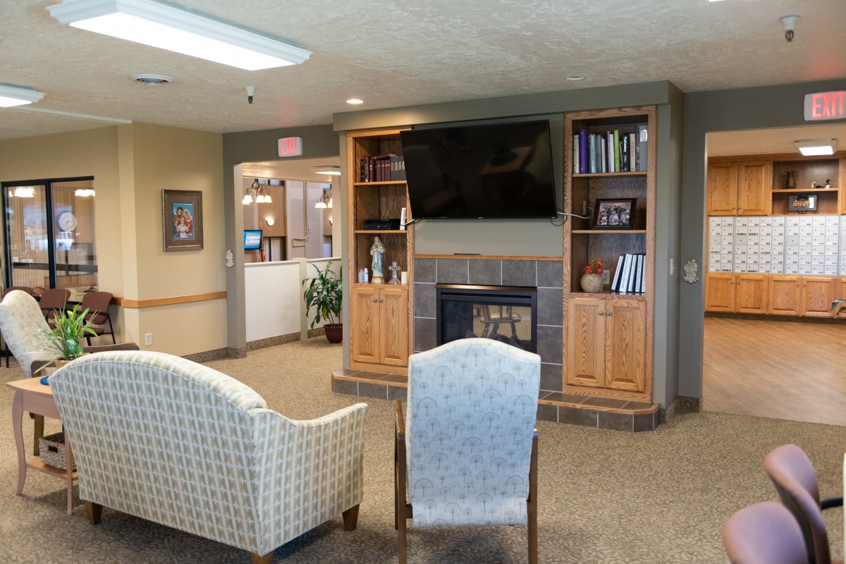 A cozy living room with a TV, fireplace, and bookshelves, featuring comfortable seating.