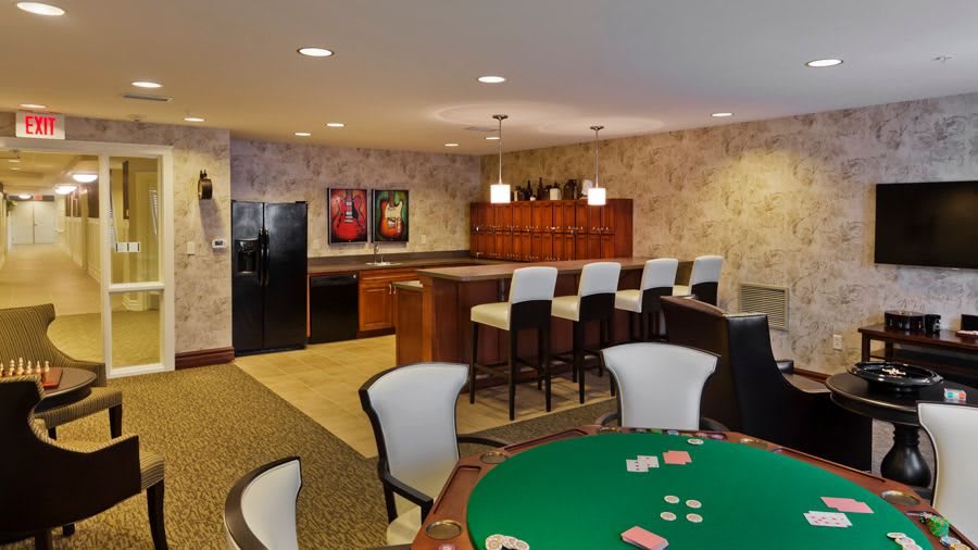 A stylish interior featuring a poker table and a bar area with modern seating.