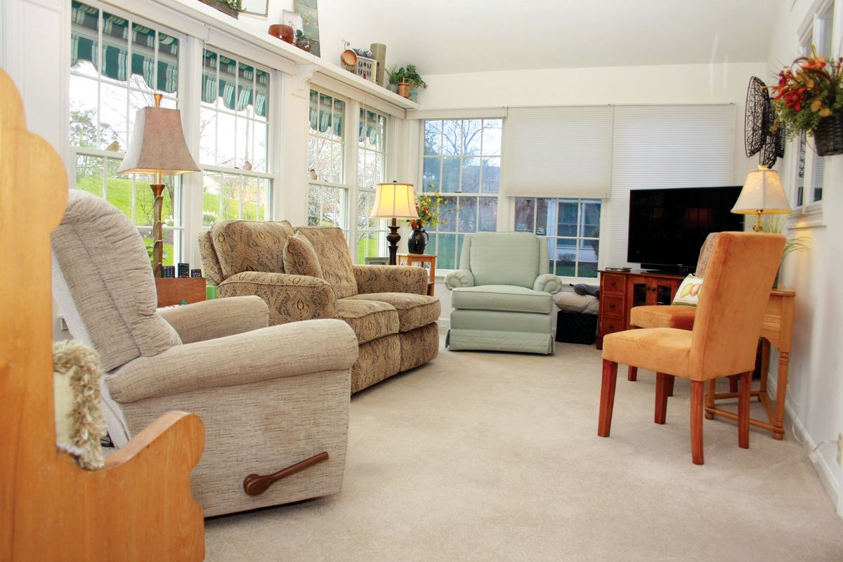 A cozy and well-lit living room with comfortable seating and large windows.