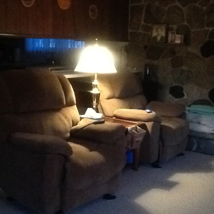 A cozy living room with recliner chairs and a warm lamp glow.