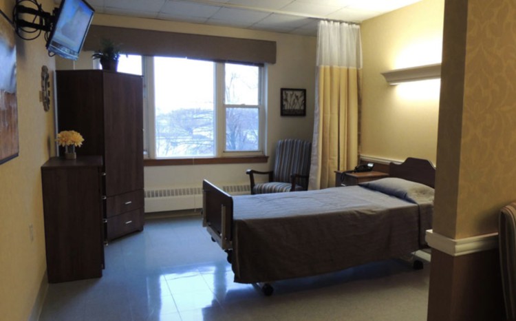 A simple hospital room with a single bed, wardrobe, and window.