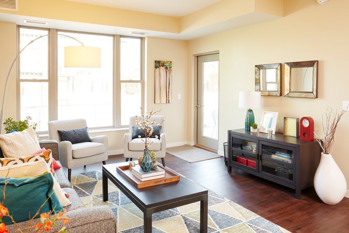 A modern living room with natural light, featuring stylish furniture and wooden flooring.