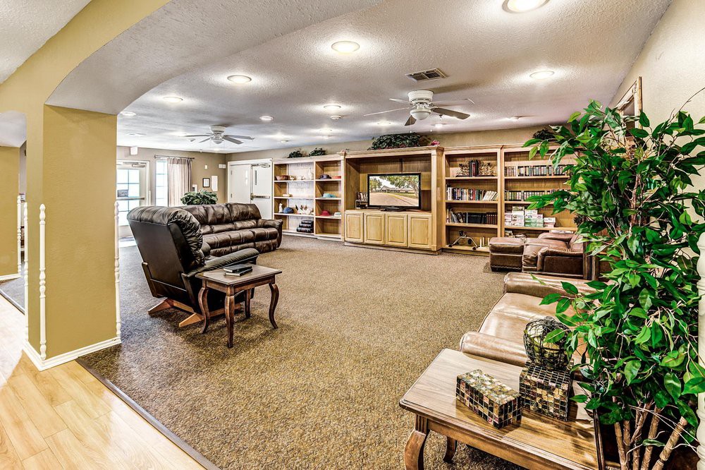 A spacious living room with comfortable seating, bookshelves, and a large television.